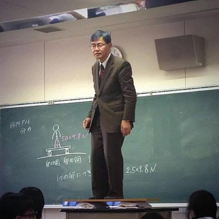 Teacher standing on top of the desk to explain the laws of physics