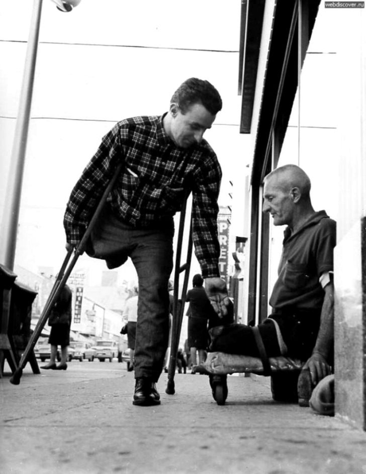 disabled man gives money to a disabled beggar