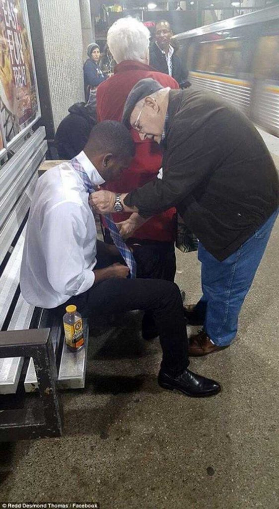 A man helps a stranger perfect his tie