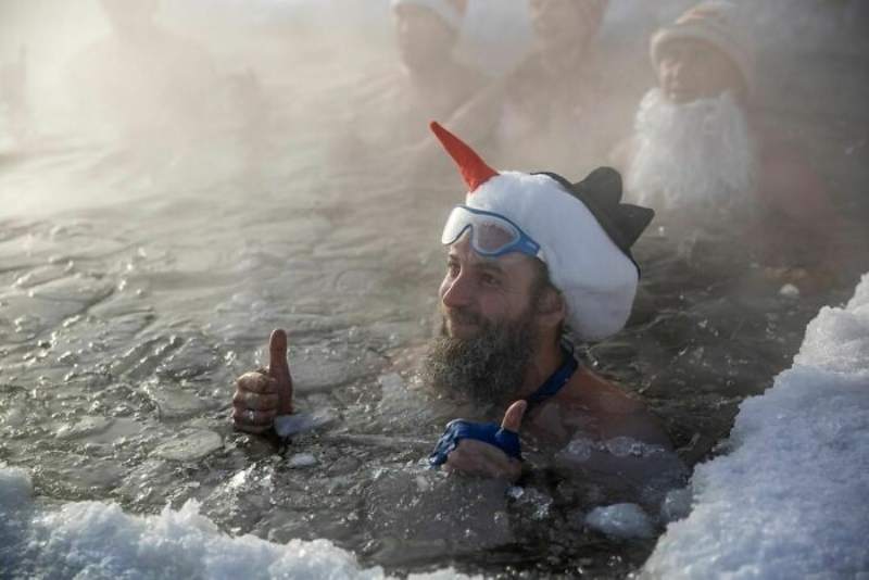 people swimming in frozen lake